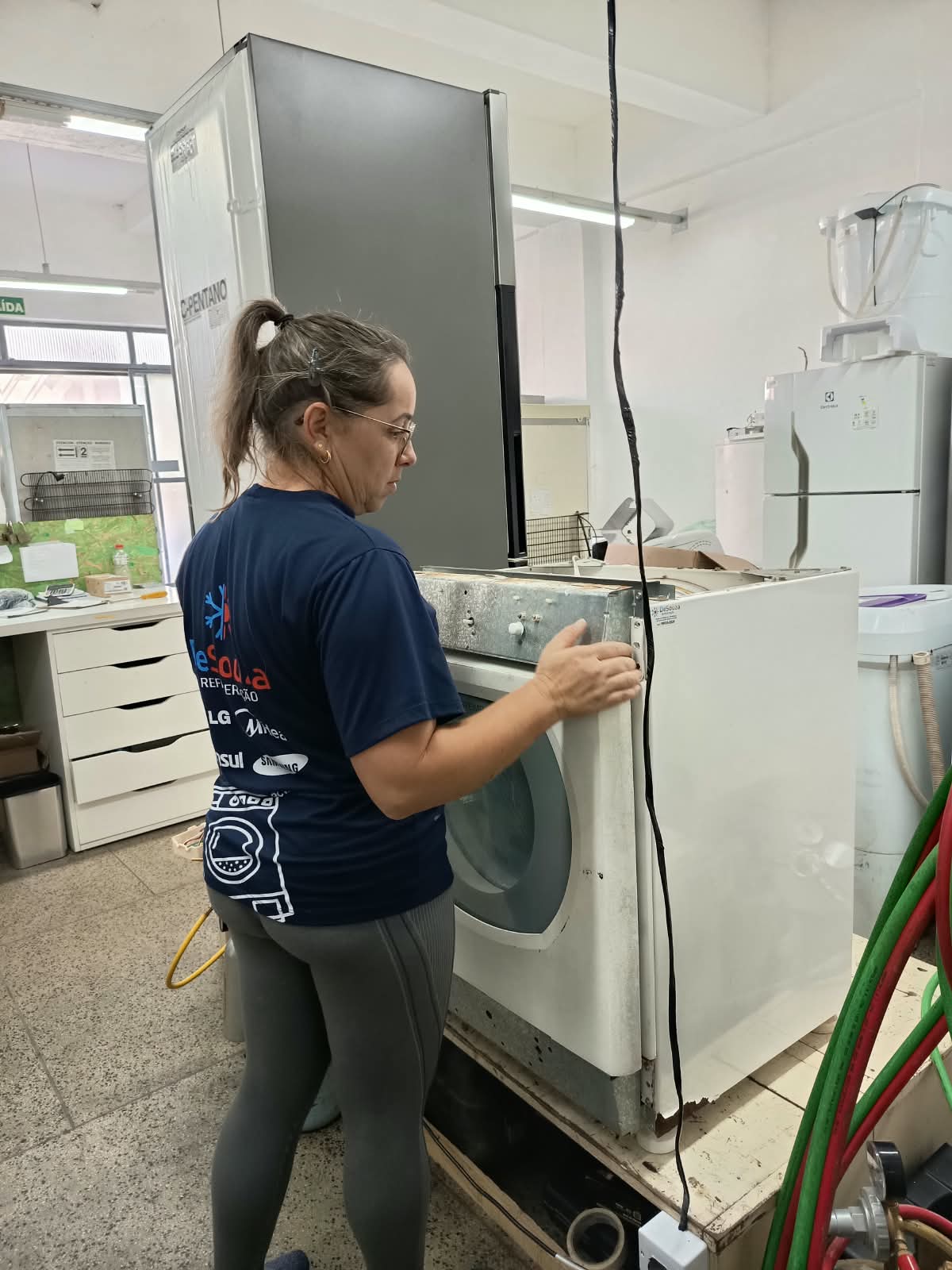 Técnica da DeSouza consertando uma lava e seca na oficina